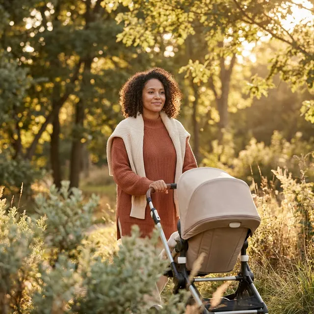 A new mom pushing a stroller through soft woodland light.